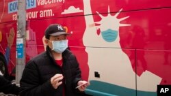 A man carries his vaccination card after receiving the Johnson & Johnson COVID-19 vaccine, Wednesday, April 7, 2021, in the Sunset Park neighborhood of New York. (AP Photo/Mark Lennihan)