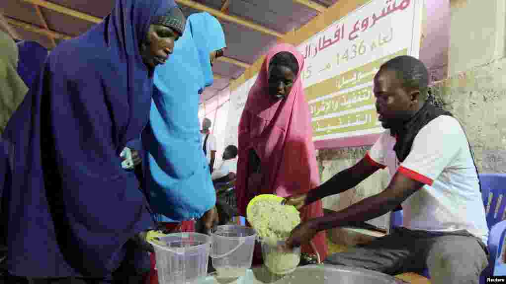 Familia za Kisomali wakipata futari katika kituo cha misaada mjini Mogadishu June 22, 2015. REUTERS/Feisal Omar - RTX1HMYN