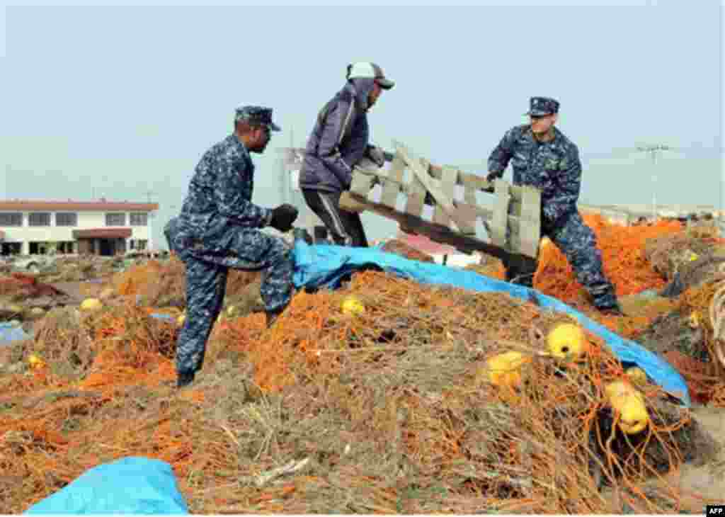 In a March 14, 2011 photo provided by the Navy Visual News Service, Navy Aerographer�s Mate 2nd Class John Dicola from New York, and Intelligence Specialist 1st Class Shakir Briggs from Orlando, Fla., helpa local civilian remove debris from the Misawa Fis