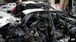 Một chiếc xe bị hư hại hoàn toàn sau vụ nổ bom trong quận Bab Touma