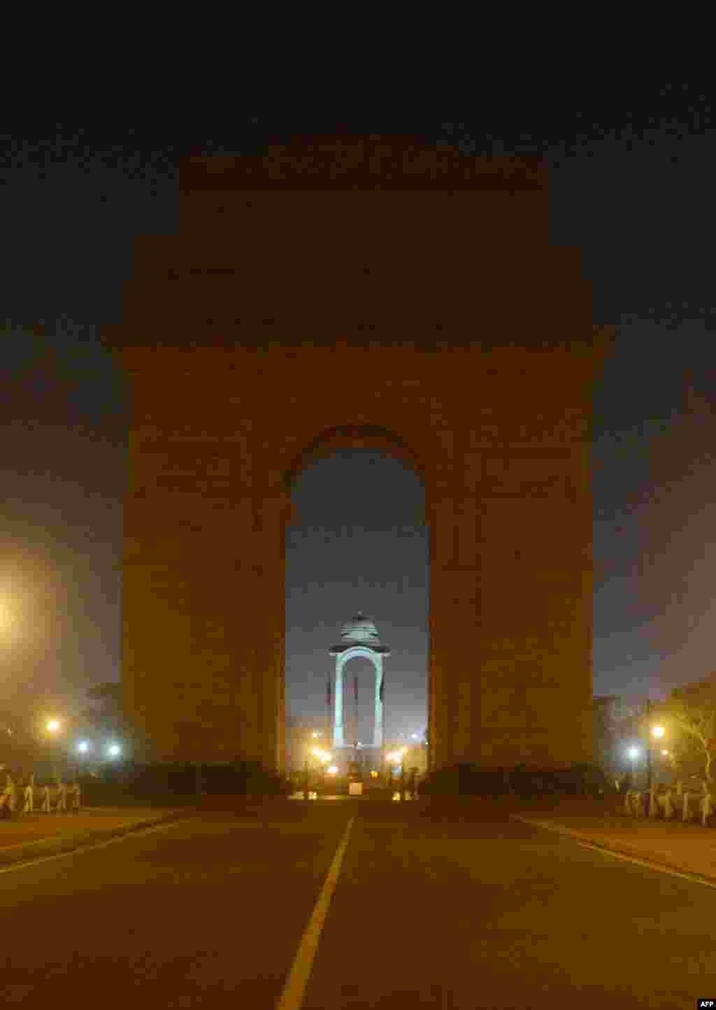 Cảnh s&aacute;t Ấn Độ nh&igrave;n tượng đ&agrave;i India Gate, với đ&egrave;n tắt trong đ&ecirc;m kỷ niệm Giờ Tr&aacute;i đất tại New Delhi.