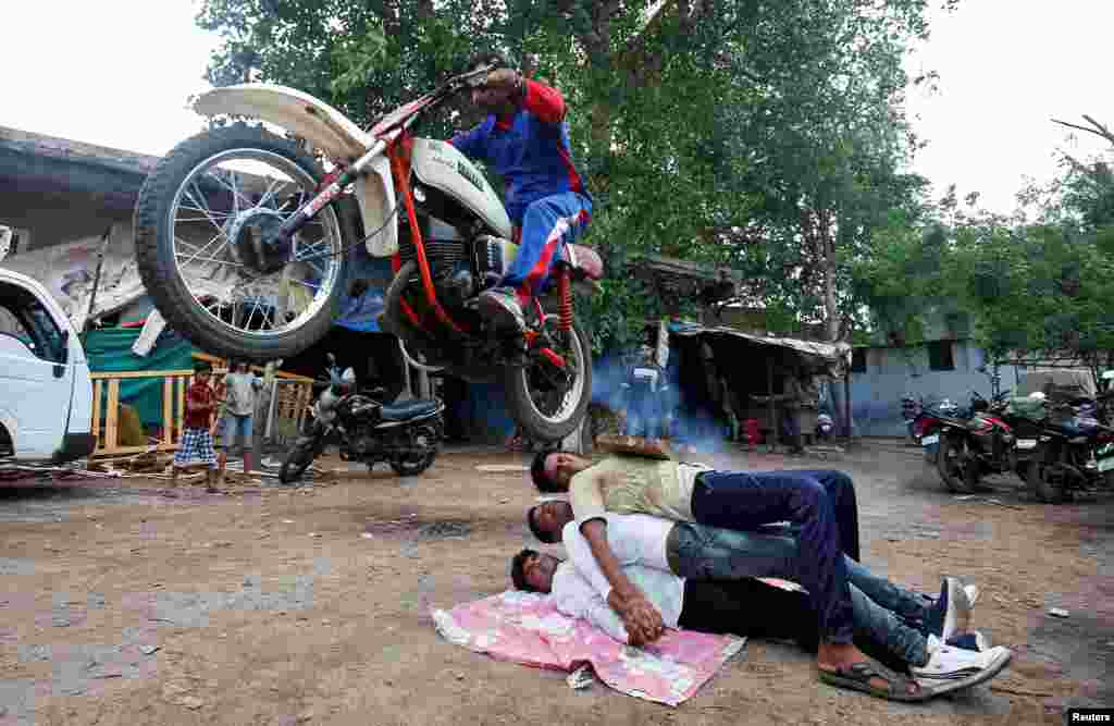 A Hindu devotee performs a stunt with his motorcycle ahead of the annual Rath Yatra, or chariot procession, in Ahmedabad, India, July 3, 2018.