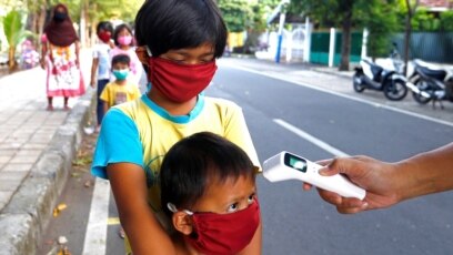 Trẻ em được kiểm tra thân nhiệt trước khi nhận thực phẩm miễn phí tại Jakarta, Indonesia, ngày 14/5/2020. 