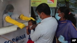 A health worker takes a nasal swab sample at a COVID-19 testing center in Hyderabad, India, Friday, Oct. 23, 2020. India reports below 60,000 new coronavirus positive cases for a fifth day as the promise of a free COVID-19 vaccine turns into a key state e