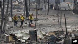 Personal del Departamento de Bomberos del Condado de San Bernardino, California, evalúan los daños en un barrio tras un incendio forestal el domingo, 29 de julio de 2018.