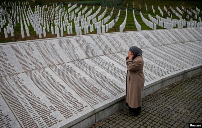 FILE - Bida Smajlovic prays near the memorial plaque with names of those killed in the Srebrenica massacre, in Potocari near Srebrenica, Bosnia and Herzegovina, March 24, 2016.