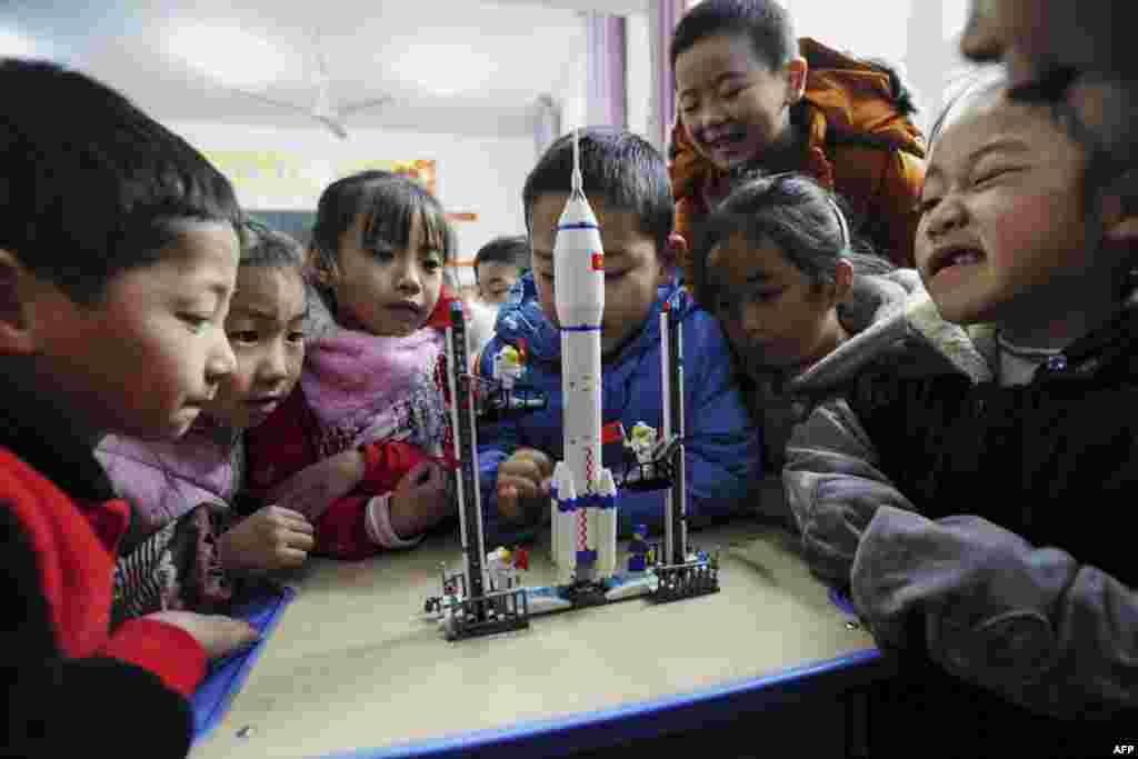Children look at a model of the Longmarch rocket during an aerospace education lesson at a primary school in Yunyang county in southwestern China&#39;s Chongqing.