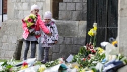 Children lay flowers outside of Windsor Castle in Windsor, England after the announcement regarding the death of Britain's Prince Philip, Friday, April 9, 2021.