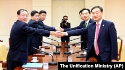 South Korea's chief delegate Lee Deok-haeng, second from right, shakes hands with North Korean counterpart Pak Yong Il, second from left, before the Inter-Korean Red Cross working level meeting at Panmunjom in Paju, South Korea, Sept. 7, 2015. 