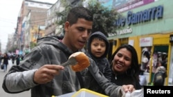 FILE - Bryant Medina, a migrant from Venezuela, sells traditional Venezuelan pastry known as bombas venezolanas at the La Victoria district in Lima, Peru, Aug. 23, 2017. 