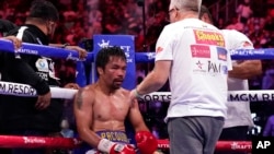 FILE - Trainer Freddie Roach speaks to Manny Pacquiao between rounds against Yordenis Ugas, of Cuba, in a welterweight championship boxing match in Las Vegas, Aug. 21, 2021. Pacquiao is officially hanging up his gloves. FILE - Trainer Freddie Roach speaks