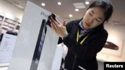 Seorang pegawai toko di Wuhan, provinsi Hubei, Tiongkok, membersihkan papan iklan iPhone 5. (Foto: Reuters)