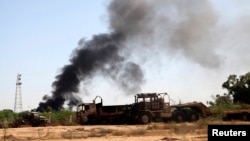 Smoke rises from the Brigade Qaqaa headquarters, a former Libyan Army camp known as Camp 7 April, following clashes between rival militias at the Sawani road district, Aug. 24,2014.