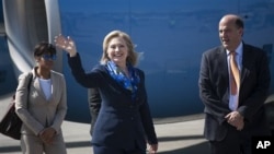 Secretary of State Hillary Rodham Clinton, center, accompanied by US ambassador to Haiti Kenneth H. Merten, right, waves to journalists upon her arrival to Port-au-Prince, Haiti, January 30, 2011.