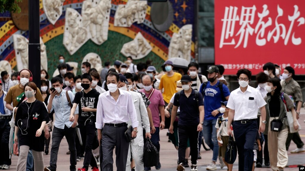 People wearing masks against the spread of the new coronavirus walk at Shibuya pedestrian crossing in Tokyo Friday, July 31, 2020. The Japanese capital confirmed Friday more than 400 new coronavirus cases. (AP Photo/Eugene Hoshiko)