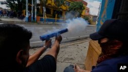 Manifestantes anti governamentais disparam contra a policia com arma de fogo de fabrico caseiro