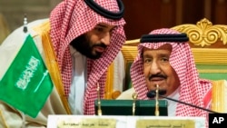 FILE - In this Dec. 9, 2018 file photo, released by the state-run Saudi Press Agency, Saudi Crown Prince Mohammed bin Salman, left, speaks to his father, King Salman, at a meeting of the Gulf Cooperation Council in Riyadh, Saudi Arabia.