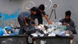FILE - Boys scavenge in a dumpster for valuables and metal cans that can be resold, in Beirut, Lebanon, June 17, 2021.