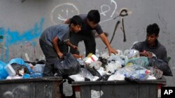 FILE - Boys scavenge in a dumpster for valuables and metal cans that can be resold, in Beirut, Lebanon, June 17, 2021.