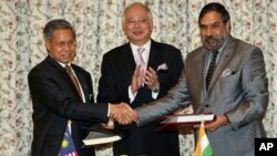 India's Commerce Minister Anand Sharma, right, shakes hand with Malaysia's International Trade and Industry Minister Mustapa Mohamed, left, as Malaysia's Prime Minister Najib Razak applauds during the signing ceremony of the Malaysia - India Comprehensive