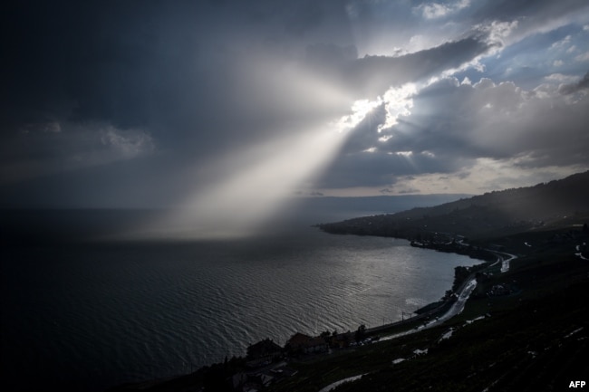 A ray of sun shines through clouds over Lake Geneva next to the Lavaux vineyard terraces near Chexbres, western Switzerland.
