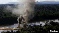 FILE - An illegal gold dredge is seen burning down at the banks of Uraricoera River during Brazil’s environmental agency operation against illegal gold mining on indigenous land, in the heart of the Amazon rainforest, in Roraima state, Brazil, April 15, 2016. 
