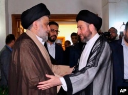 In this photo provided by the Sadr Media Office, Shiite cleric Muqtada al-Sadr, left, greets Shiite leader Ammar al-Hakim on his arrival for their meeting in Baghdad, Iraq, May 22, 2018.