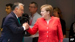 Hungarian Prime Minister Viktor Orban, left, greets German Chancellor Angela Merkel during a breakfast meeting at an EU summit in Brussels, Friday, June 29, 2018.