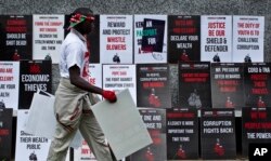 FILE - A protester walks past rows of placards during an anti-corruption demonstration in downtown Nairobi, Kenya, Dec. 1, 2015.