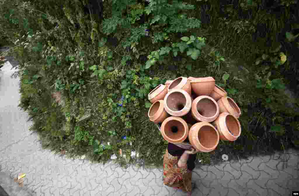 A Kashmiri woman carries pottery items in a basket to sell in the market on the outskirts of Srinagar, the summer capital of Indian Kashmir.