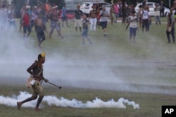 An indigenous man runs amid tear gas fired by police during a protest for the demarcation of indigenous lands outside the National Congress in Brasilia, Brazil, April 25, 2017.