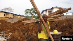 FILE - A construction worker carries timber at a housing project being built in an old cocoa-producing community just outside Equatorial Guinea's capital Malabo, February 5, 2014. 