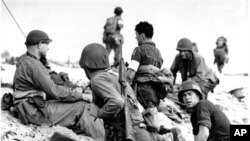 American troops lay low under the fire of Nazi guns on the beach of southern France on D-Day, June 6, 1944