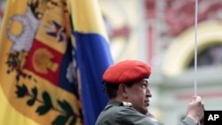 Venezuela's President Hugo Chavez hoists the national flag as he attends a ceremony in Caracas July 14, 2011