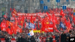 Manaifestantes portando banderas rojas marcha por las calles de Moscú en el Día Internacional del Trabajo el martes, 1 de mayo, de 2018.