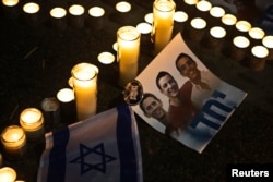Candles placed next to a picture of three Israeli teenagers who were abducted and killed, in Tel Aviv's Rabin Square, June 30, 2014.