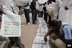 People read local newspapers with headlines stating, "I saw my classmate in the video," referring to the kidnapped girls of the Chibok school shown in a video released May 12 by Boko Haram in Abuja, Nigeria, May 14, 2014.