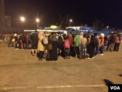 Refugees crowd around bus drivers in Athens that promise to take them directly to the Macedonia border, Athens, Sept. 2015. (H.Murdock/VOA)