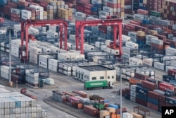 A cargo truck drives amid stacked shipping containers at the Yangshan port in Shanghai, Thursday, March 29, 2018.