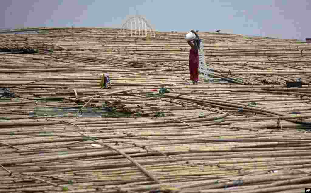 A woman bathes on floating bamboo in the River Brahmaputra in Gauhati, India,