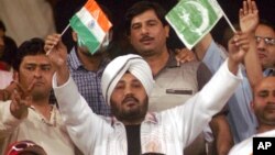 FILE - Indian pop star Daler Mehndi, center, waves Indian and Pakistani flags while watching a cricket match in Lahore, Pakistan, March 24, 2004.