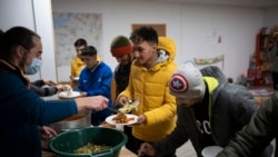 Aymen Jarnane, 23, from Morrocco is given dinner at a migrant center in Briançon, France on December 10, 2021. (AP Photo/Daniel Cole)