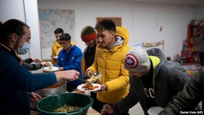 Aymen Jarnane, 23, from Morrocco is given dinner at a migrant center in Briançon, France on December 10, 2021. (AP Photo/Daniel Cole)