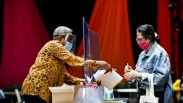 A voter, right, checks in with an election worker before casting her ballot in the Pennsylvania primary in Philadelphia, Tuesday, June 2, 2020. (AP Photo/Matt Rourke)