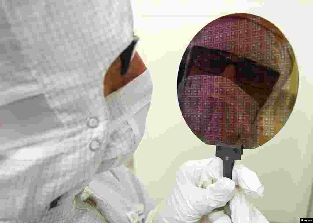 Achim Trautmann of German auto parts supplier Robert Bosch holds up a Wafer in the Corporate Research Applied Research Microsystem Technologies Office by Bosch in Gerlingen-Schillerhoehe near Stuttgart.