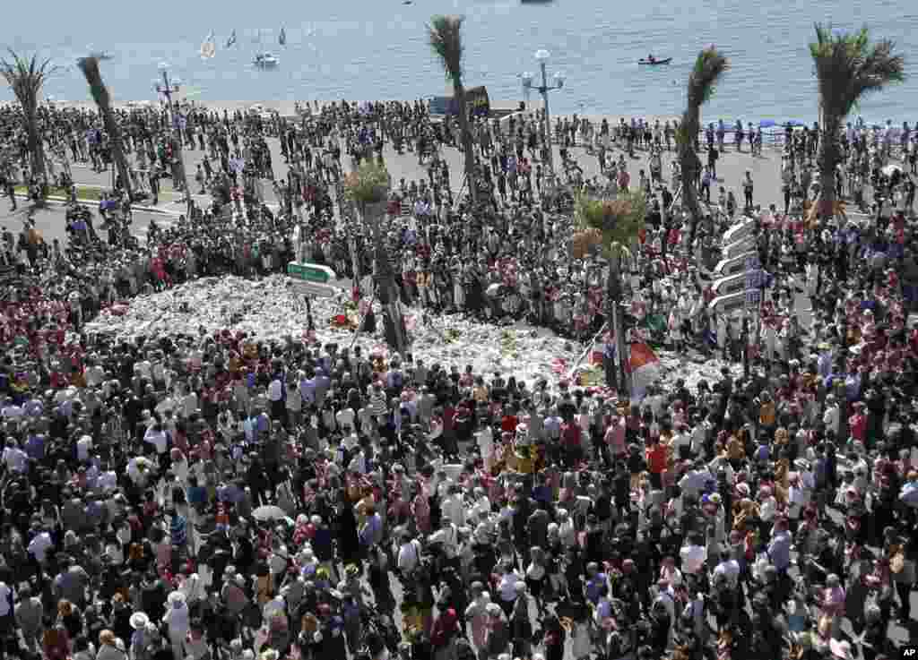 People gather at a makeshift memorial to observe a minute of silence to honor 84 people killed by a truck rampage on the famed Promenade des Anglais in Nice, southern France.