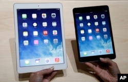 An Apple employee demonstrates the new iPad Air, left and iPad mini, Oct. 22, 2013, in San Francisco.