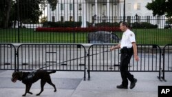 A member of the Secret Service Uniformed Division with a K-9 walks along the perimeter fence along Pennsylvania Avenue outside the White House in Washington, Sept. 22, 2014. 