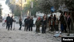 Cư dân nhìn một tòa nhà bị hư hại sau một vụ oanh kích mà các nhà hoạt động nói rằng do máy bay của lực lượng trung thành với Tổng thống Syria al-Assad thực hiện trong vùng ngoại ô Damascus, 25/12/14