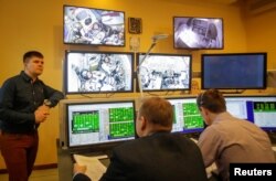 Specialists watch broadcasts from the Soyuz spacecraft showing astronaut David Saint-Jacques of Canada, Oleg Kononenko of Russia and astronaut Anne McClain of the U.S. attending the final qualification training for their upcoming space mission in Star City near Moscow, Russia, Nov. 14, 2018.